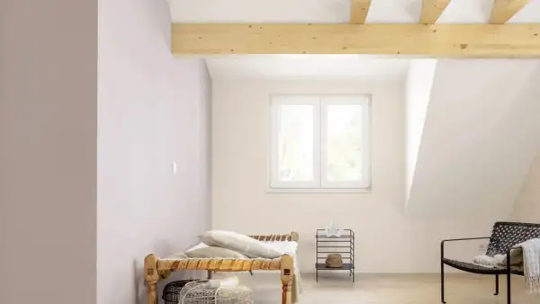Pokój na poddaszu z drewnianymi belkami i oknem. Dowiedz się, jak malować skosy, by stworzyć przytulną przestrzeń.